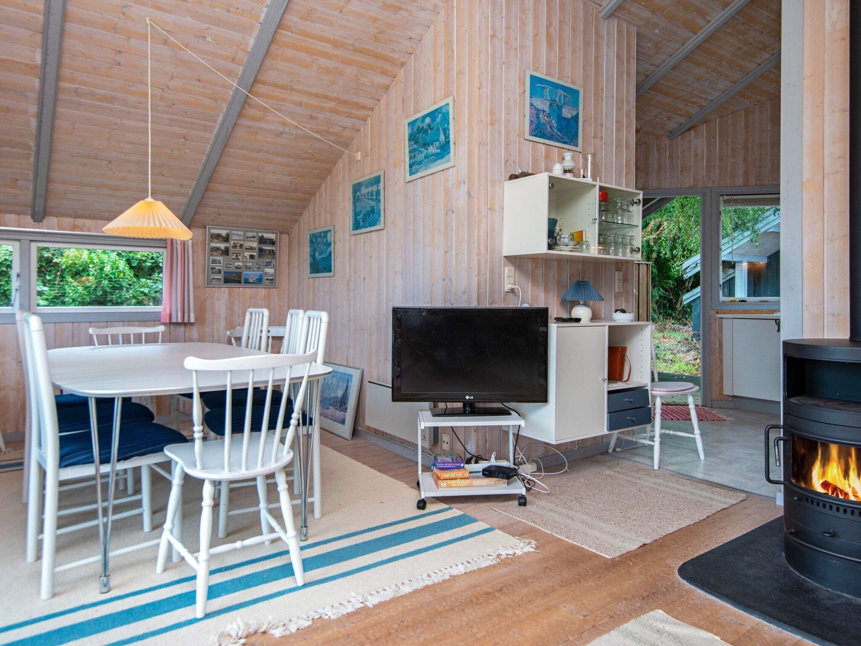 Ein gemütliches Wohnzimmer mit Fernseher, Kamin, Essbereich und Holzwänden.
