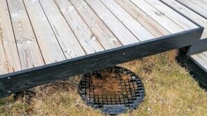 Een houten terras met een metalen barbecue.