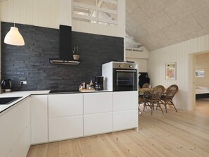 A modern kitchen with a black brick backsplash, white cabinetry, and a built-in oven. - 5 Star Holiday Home in Lokken (Lokken)