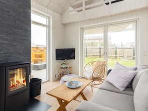 A cozy living room with a fireplace, a TV, and a sofa. - 5 Star Holiday Home in Lokken (Lokken)