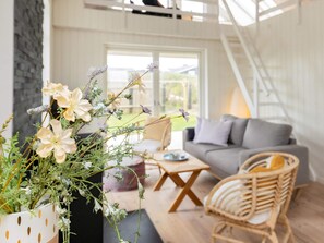 A modern living room with a sofa, a wicker chair, and a coffee table. - 5 Star Holiday Home in Lokken (Lokken)