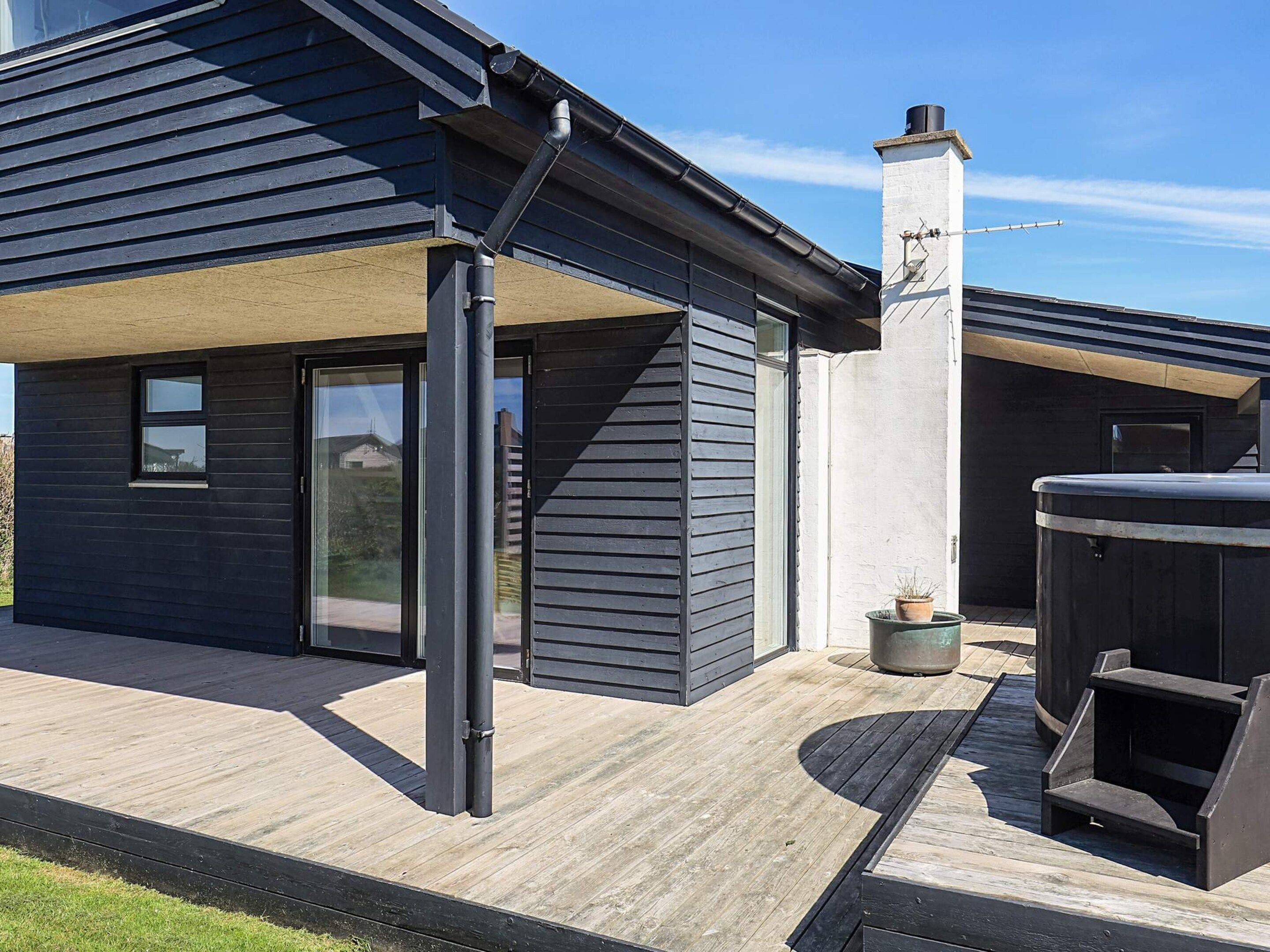 Een modern huis met terras, schoorsteen en een jacuzzi.