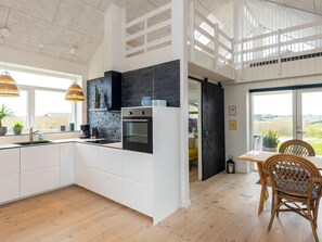 A modern kitchen with white cabinetry, a black backsplash, and a built-in oven.