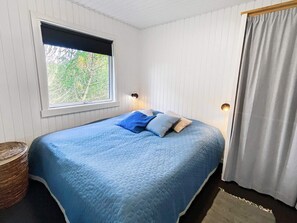 Ein Schlafzimmer mit Bett, Fenster und Vorhang.