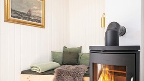 Een gezellige kamer met een houten bank, een bont deken en een zwart houtkacheltje.