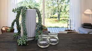 Een houten tafel met een potplant, een vaas en drie glazen kandelaars.