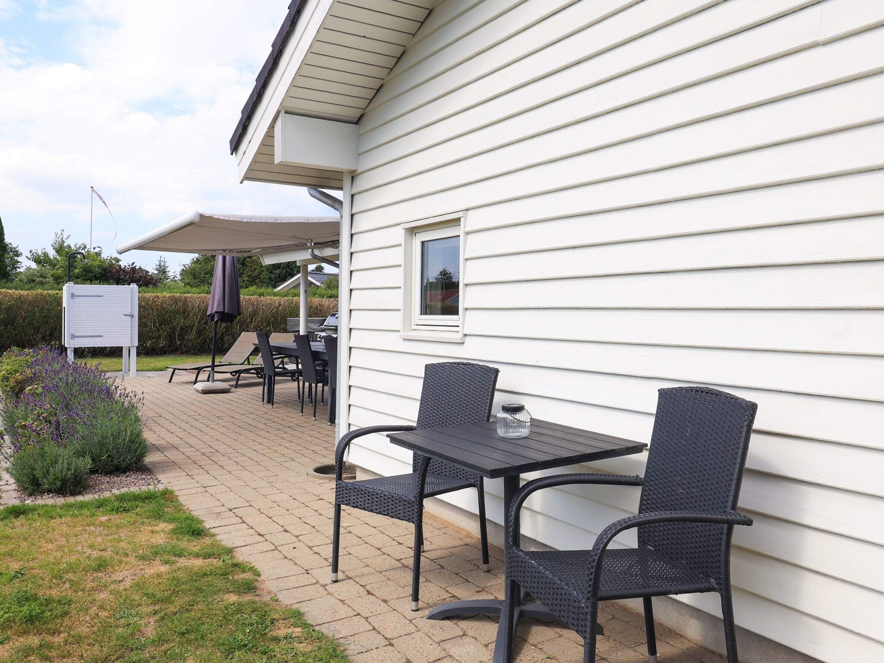 Une terrasse extérieure avec une table et des chaises, un espace abrité et un panneau d’affichage.