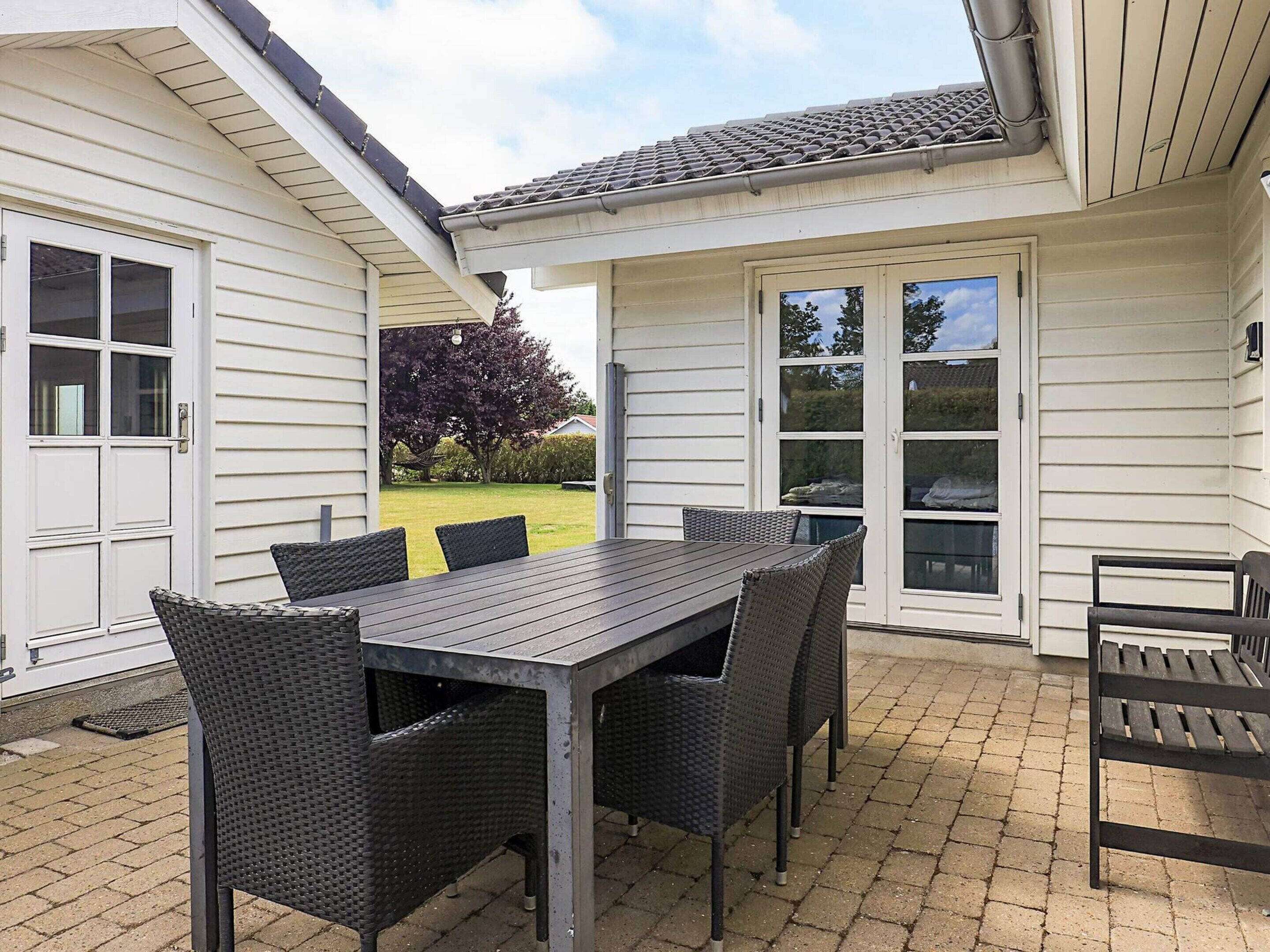 A patio with a table and chairs, a covered area, and a view of the surrounding landscape.