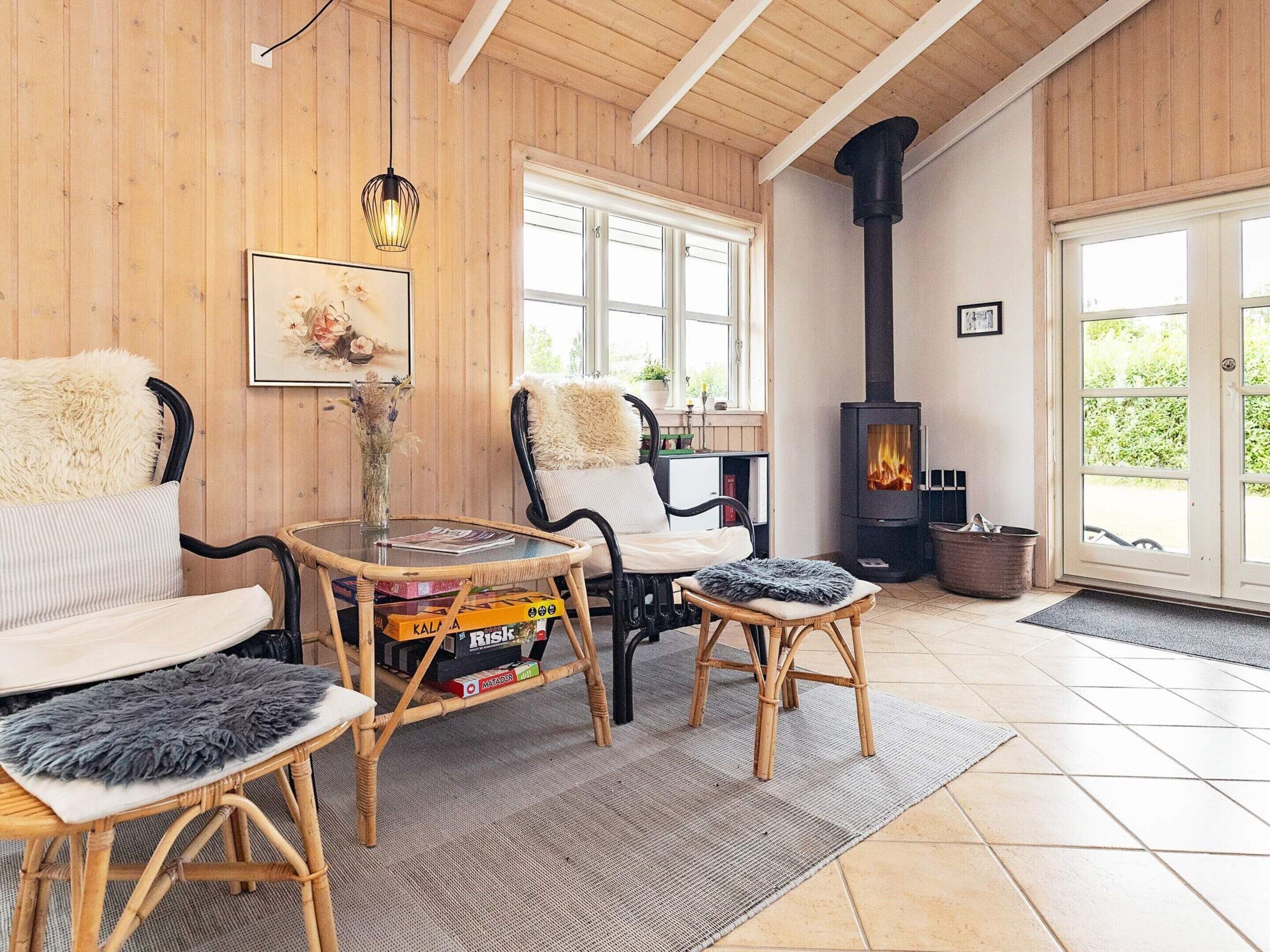A cozy room with a fireplace, wicker furniture, and a large window.