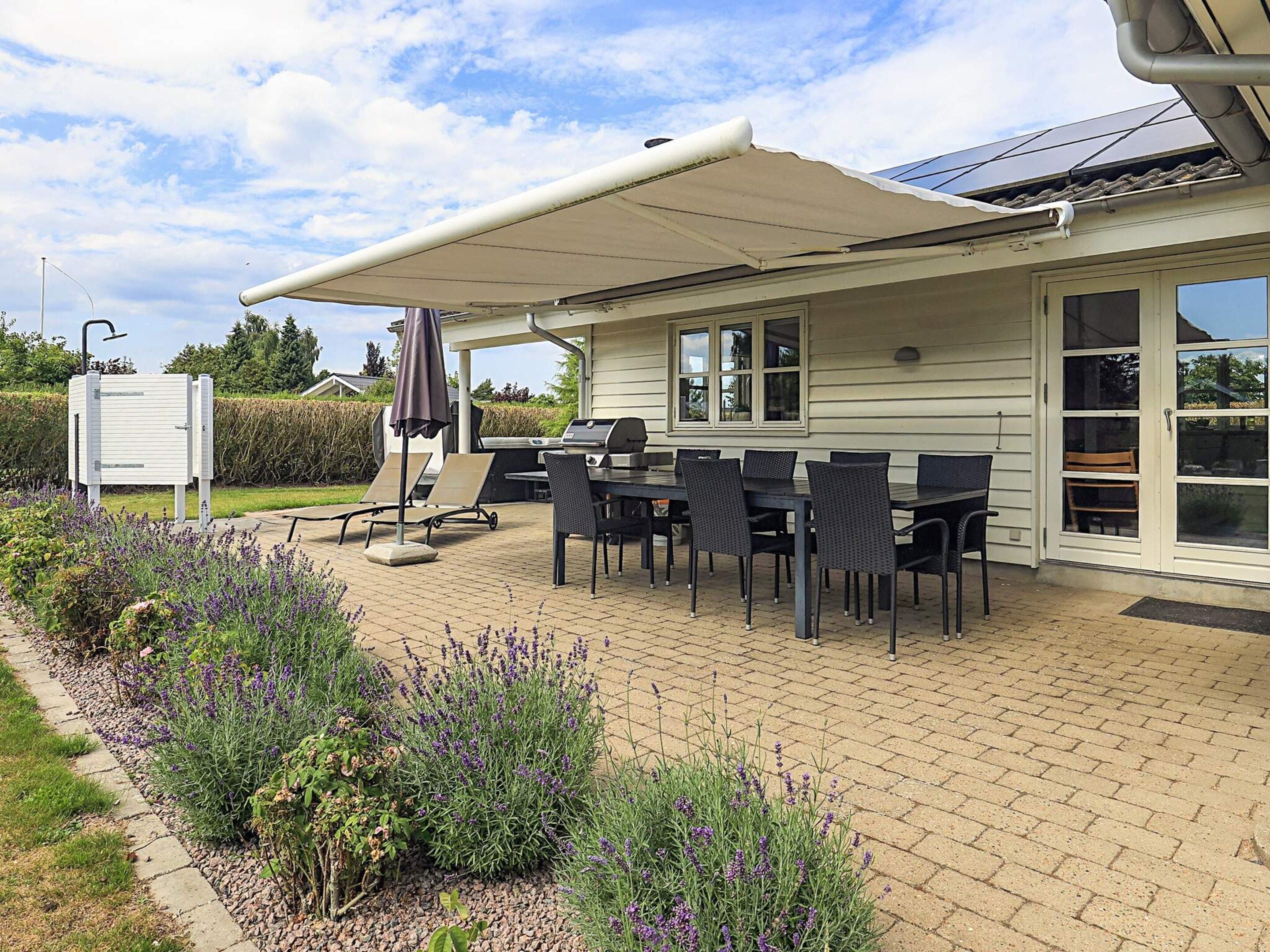Une terrasse extérieure avec une table et des chaises, un barbecue et un espace abrité.