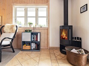 A cozy room with a fireplace, a bookshelf, a chair, and a window. - 5 Star Holiday Home in Otterup (Otterup)