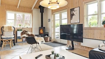 Uma sala de estar aconchegante com lareira, televisão e área de estar confortável.