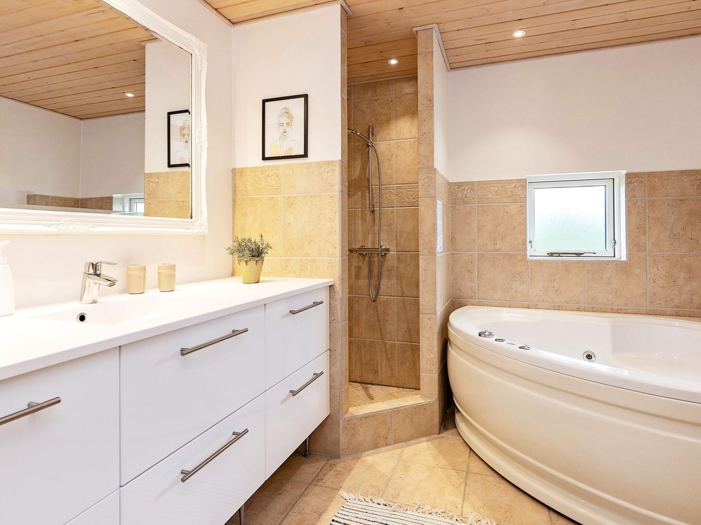 Une salle de bain moderne avec une grande baignoire, une douche et un meuble-lavabo doté de tiroirs et d’un miroir.