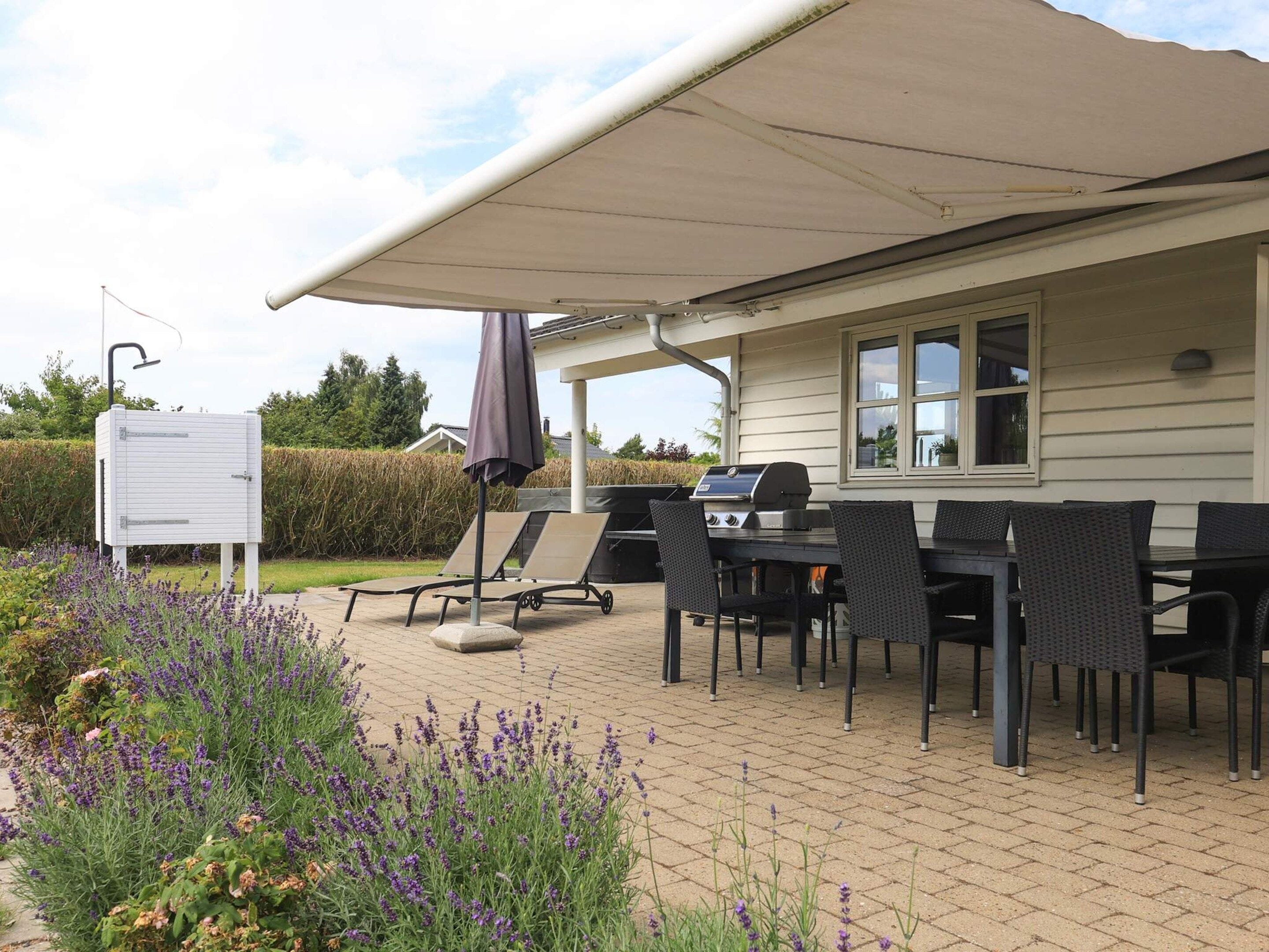 Eine Terrasse im Freien mit Grill, Liegestühlen und einer überdachten Sitzgruppe.