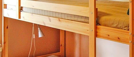 Een stapelbed met een onderbed, hoofdbord en bedlampje.