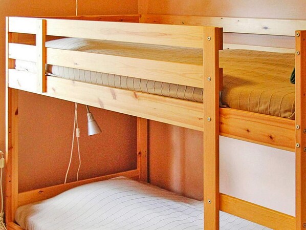 A bunk bed with a lower bunk, a headboard, and a bedside lamp.