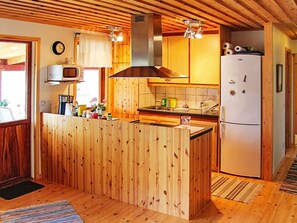 A kitchen with wooden cabinets, a microwave, a stove, and a refrigerator. - 6 Person Holiday Home in Vena (Hultsfred)