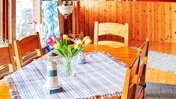 A wooden dining table with chairs, a vase with flowers, and a lighthouse model.