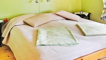 A bed with a headboard, two pillows, a bedside table with a lamp, and a nightstand with a clock.