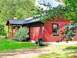 A red wooden house with a small porch and a chimney. - 6 Person Holiday Home in Vena (Hultsfred)