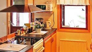 A compact kitchen with a stove, oven, microwave, and a clock on the wall. - 6 Person Holiday Home in Vena (Hultsfred)