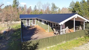 A wooden cabin with a covered patio, large windows, and a metal roof. - 6 Person Holiday Home in Jerup (Jerup)
