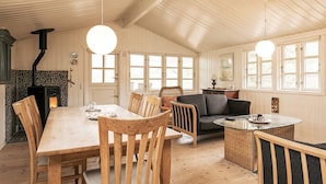A cozy room with a wooden dining table, chairs, a sofa, and a fireplace. - 6 Person Holiday Home in Jerup (Jerup)