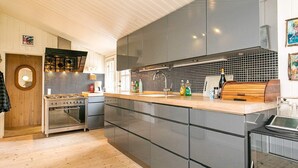 A modern kitchen with grey cabinets, a wooden countertop, and stainless steel appliances. - 6 Person Holiday Home in Jerup (Jerup)