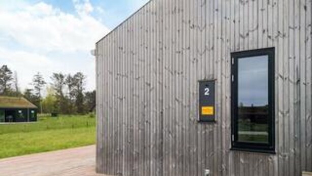 Un edificio moderno con rivestimento in legno, una finestra a cornice nera e un piccolo cartello con il numero '2'.