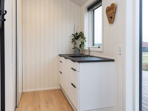 A small, narrow kitchen with white cabinetry, a black countertop, and a window above the sink.