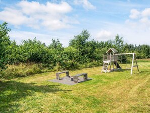 A playground with a wooden playhouse, swings, and a slide.