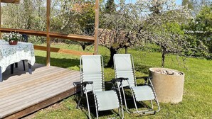 Una terraza de madera con una mesa, sillas, una pérgola y una jardinera grande.