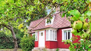Una casa roja con cimientos de piedra, ventanas blancas y techo rojo.