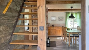 Una escalera de madera conduce a una cocina con una mesa y sillas.