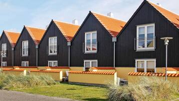 Sorte bygninger med orange tage og hvide vinduer i en række.