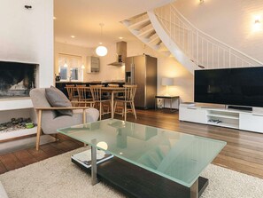 A modern living room with a glass coffee table, a sofa, a TV, and a staircase. - 4 Star Holiday Home in Skagen (Skagen)