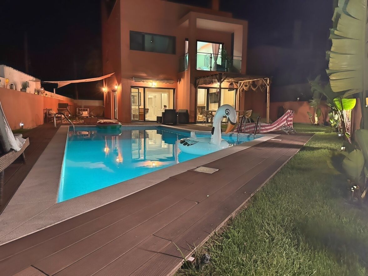 A swimming pool with a swan decoration, surrounded by a wooden deck and a grassy area.