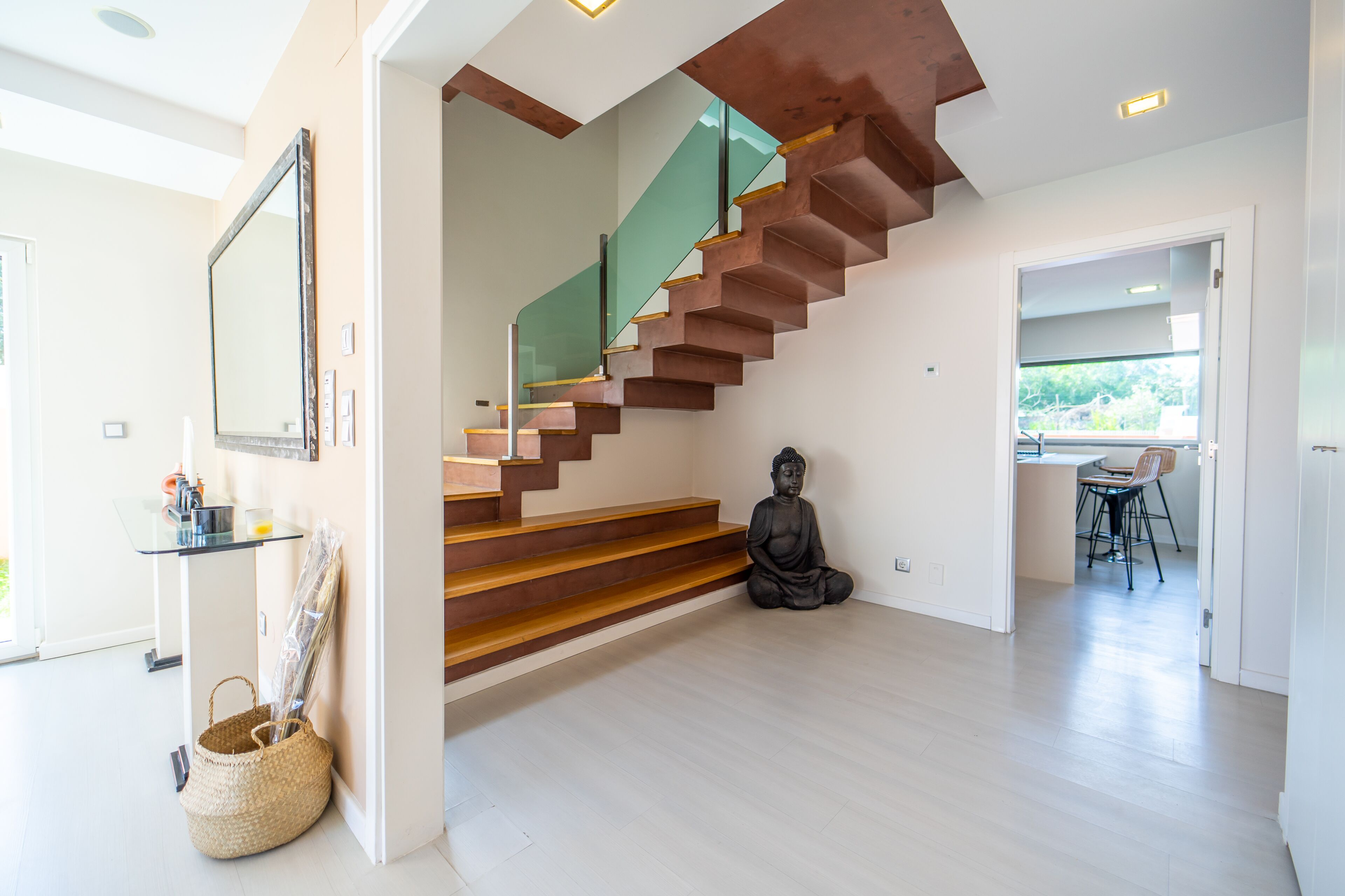 Un interior moderno con una escalera, una estatua y un área de comedor.