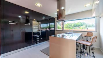 A modern kitchen with dark cabinetry, a central island, and bar stools.