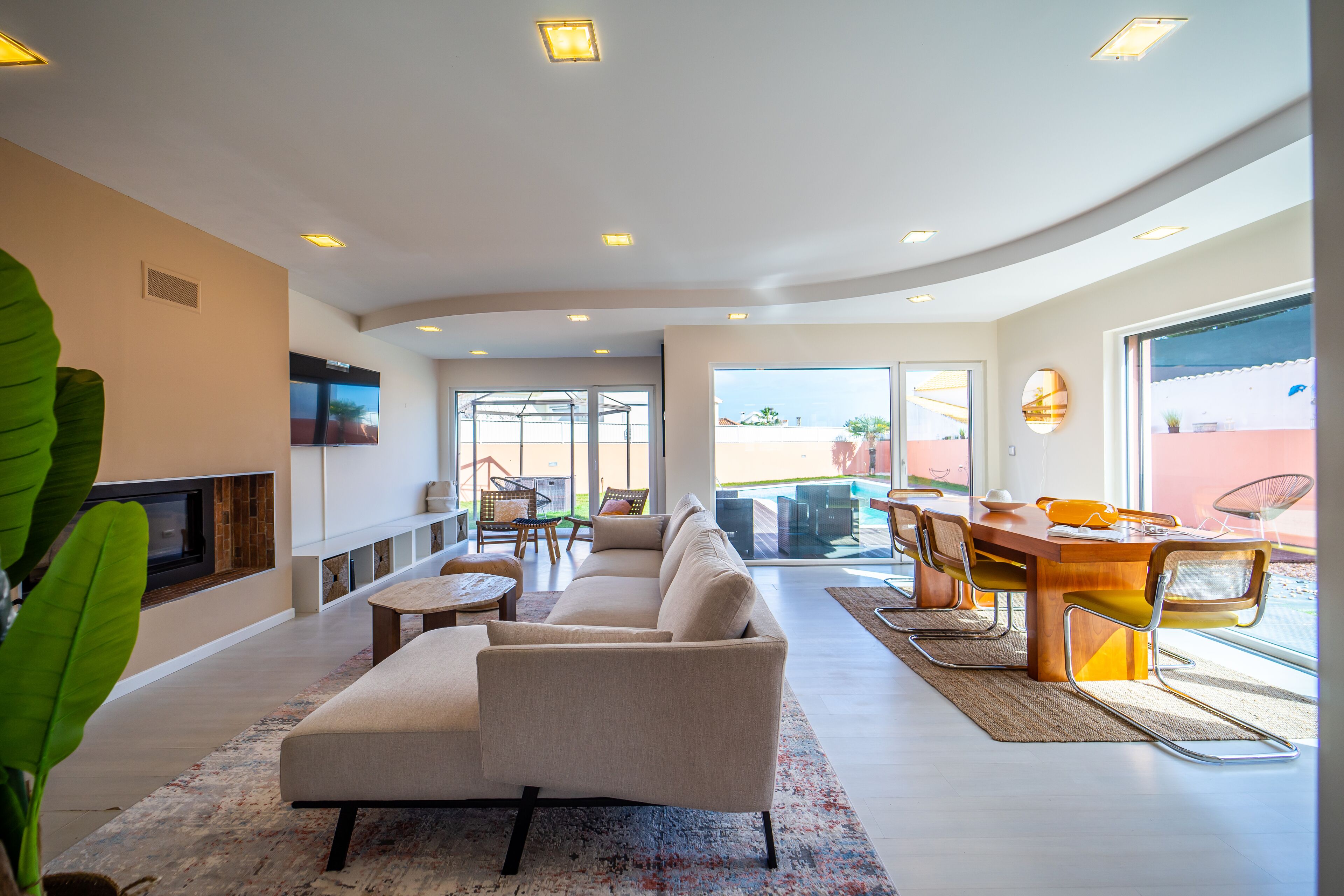 A modern living room with a sofa, coffee table, and dining area with chairs and a table.