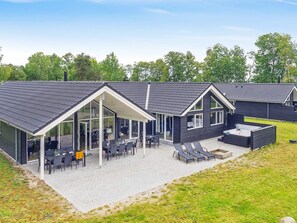 A modern building with a covered patio area, outdoor seating, and a hot tub. - 5 Star Holiday Home in Vaeggerlose (Vaeggerlose)