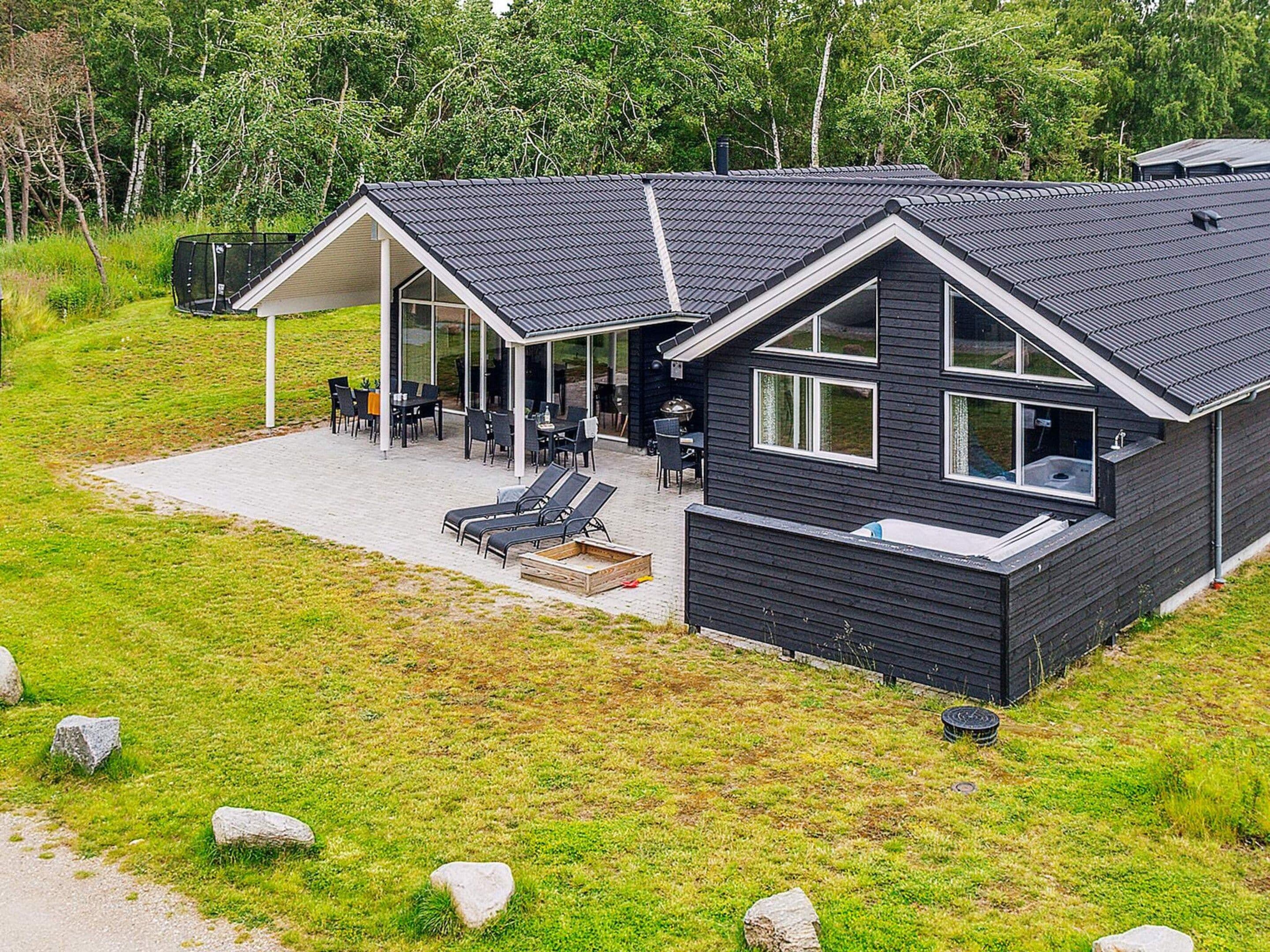Una casa moderna con un porche cubierto, mobiliario exterior y un jacuzzi.