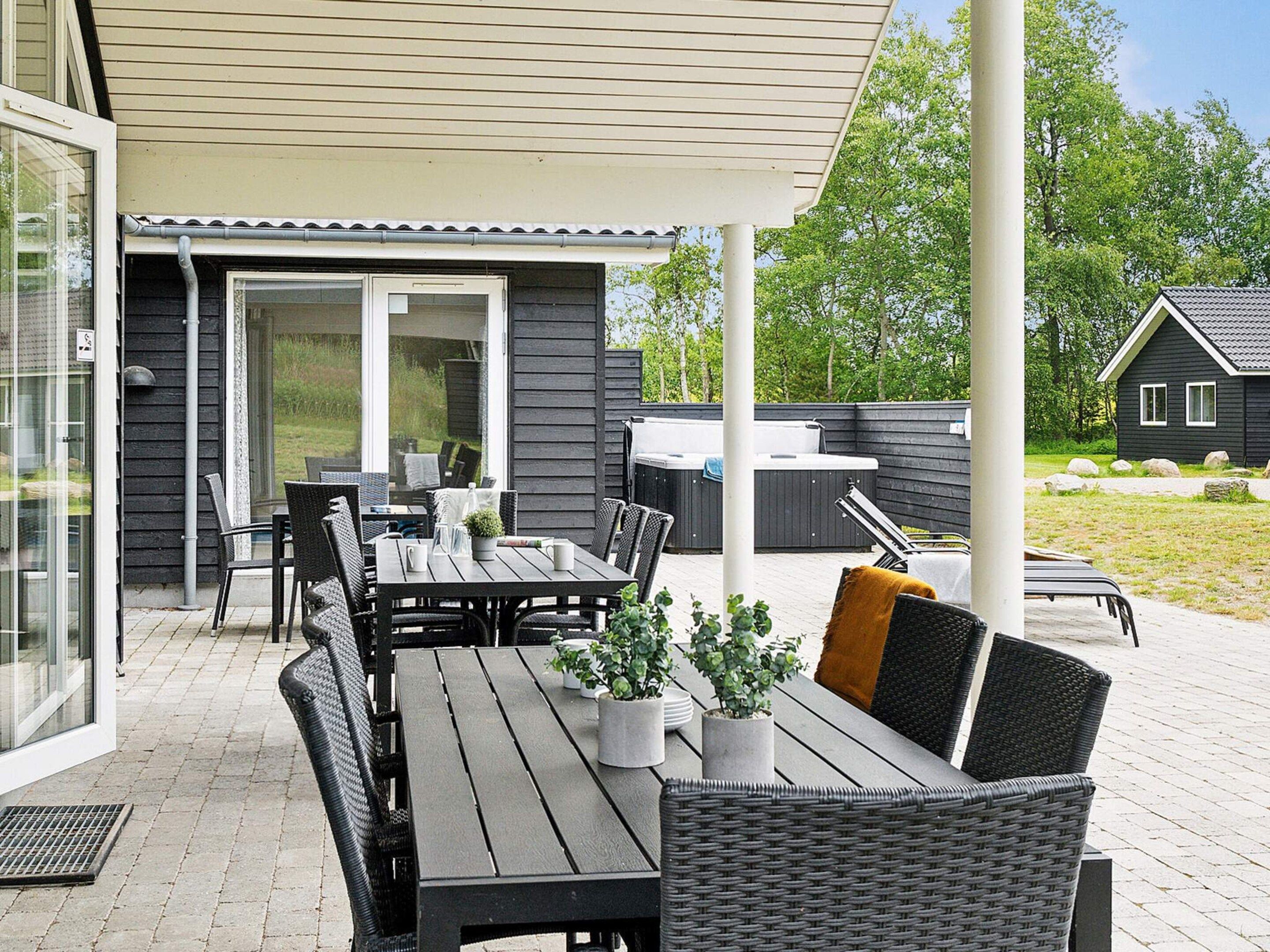 An outdoor patio with a table and chairs, a hot tub, and a covered seating area.