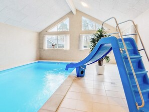 An indoor swimming pool with a blue slide and a ladder. - 5 Star Holiday Home in Vaeggerlose (Vaeggerlose)