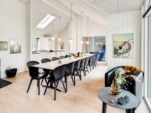 A modern dining area with a long table, black chairs, pendant lighting, and a view of a swimming pool. - 5 Star Holiday Home in Vaeggerlose (Vaeggerlose)