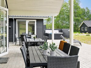 An outdoor patio area with a table and chairs, a hot tub, and a covered seating area. - 5 Star Holiday Home in Vaeggerlose (Vaeggerlose)