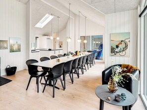 A modern dining area with a long table, black chairs, pendant lighting, and a view of a swimming pool. - 5 Star Holiday Home in Vaeggerlose (Vaeggerlose)