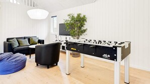 Una sala de estar moderna con una mesa de fútbol de mesa, un sofá, una mesa de centro y una planta en maceta.