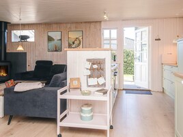 Una sala de estar acogedora con un sofá, una mesita, una chimenea y vistas al exterior.