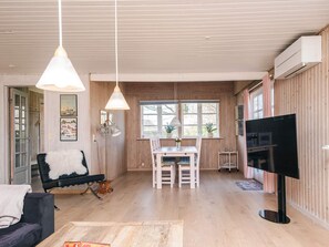 Amplia sala de estar con una mesa de comedor, sillas, un sofá, un televisor y paredes de madera.